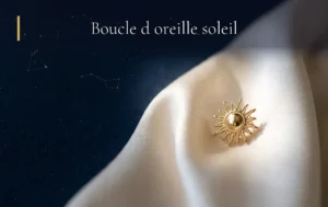 Une délicate boucle d'oreille soleil dorée posée sur un tissu crème lumineux dans une ambiance céleste et mystique.