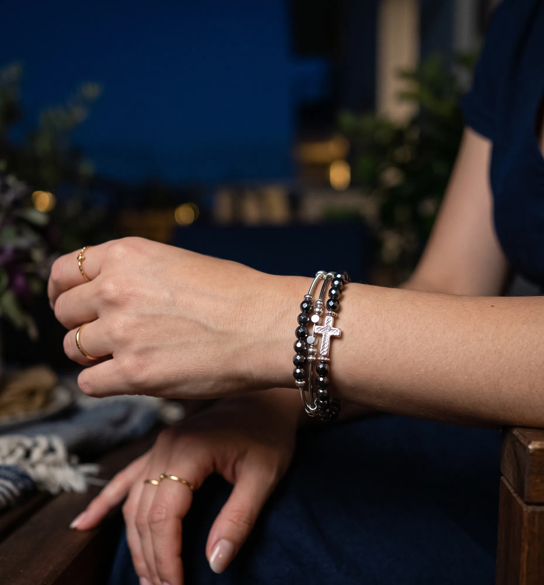 Bracelet croix en hématite aux reflets métalliques captant la lumière de la lune.
