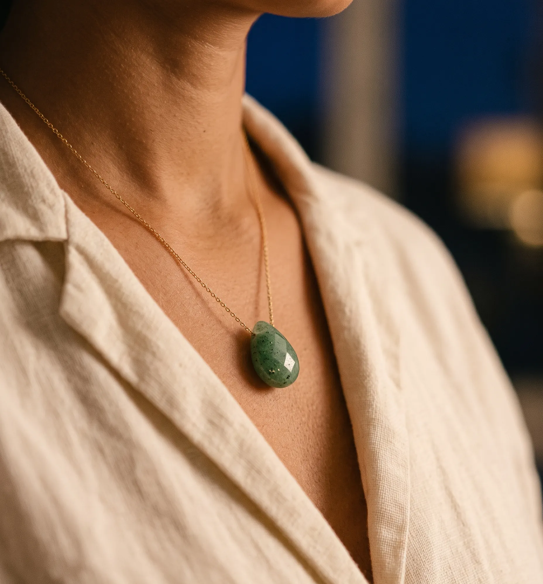 Pendentif en pierre verte posé près du cœur, symbolisant la résonance avec le chakra du cœur.