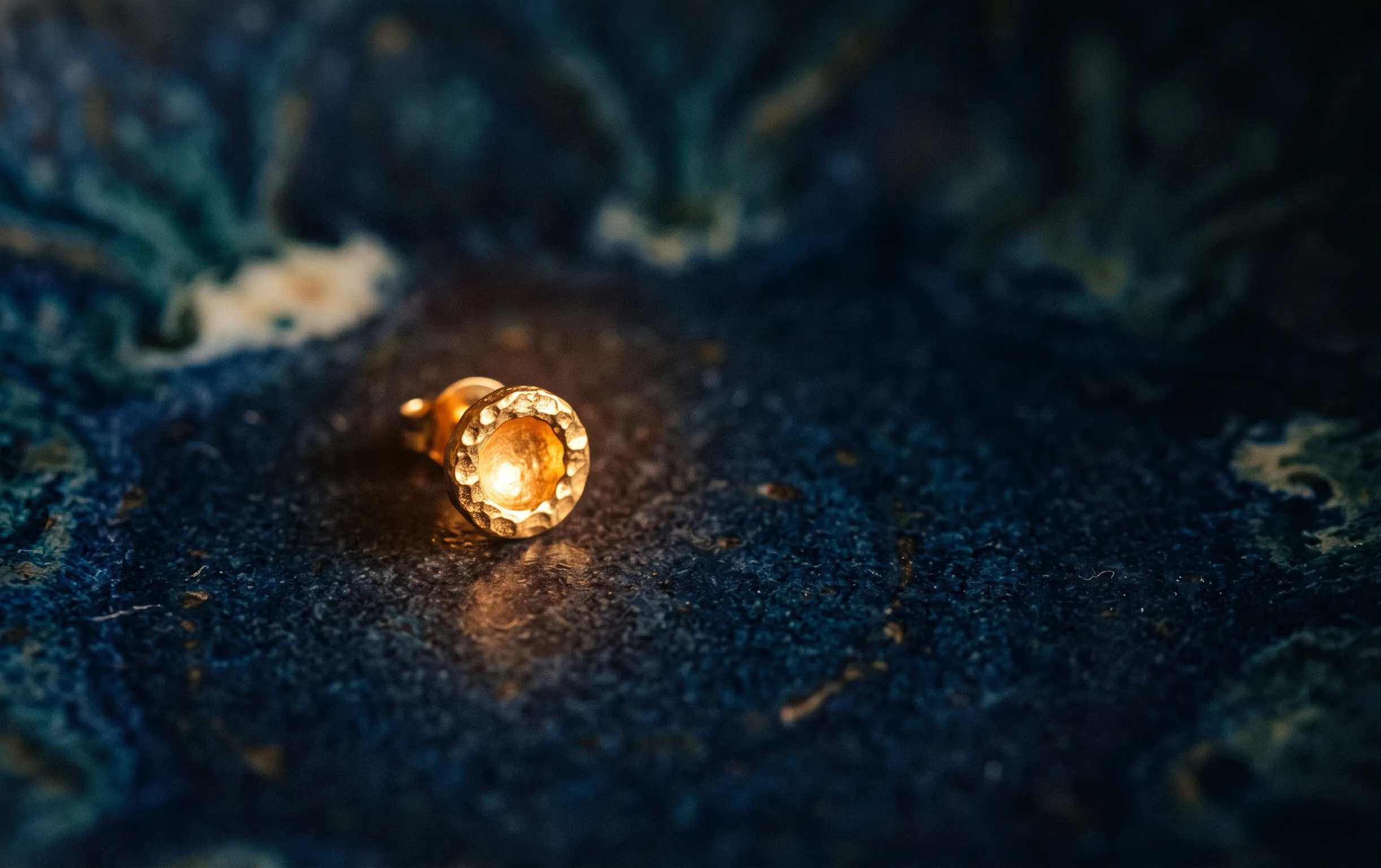 piercing tragus : Un petit clou doré étincelle sous un éclairage délicat et mystique