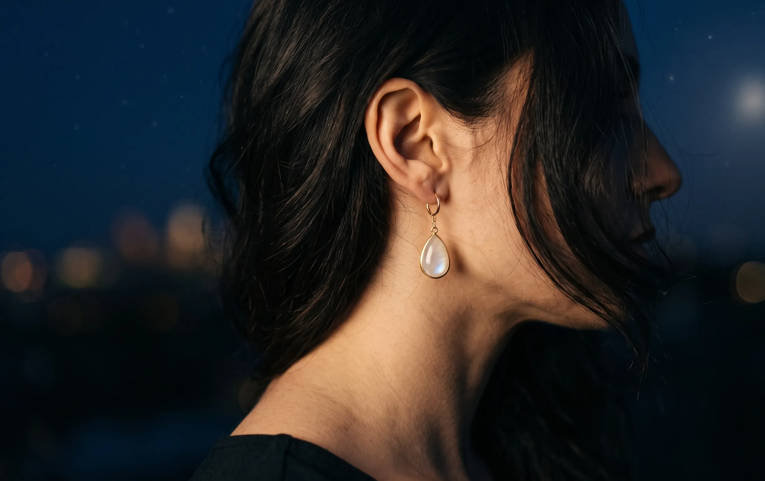 Gros plan sur une femme portant une élégante boucle d'oreille en forme de goutte d'eau sous une douce lumière lunaire